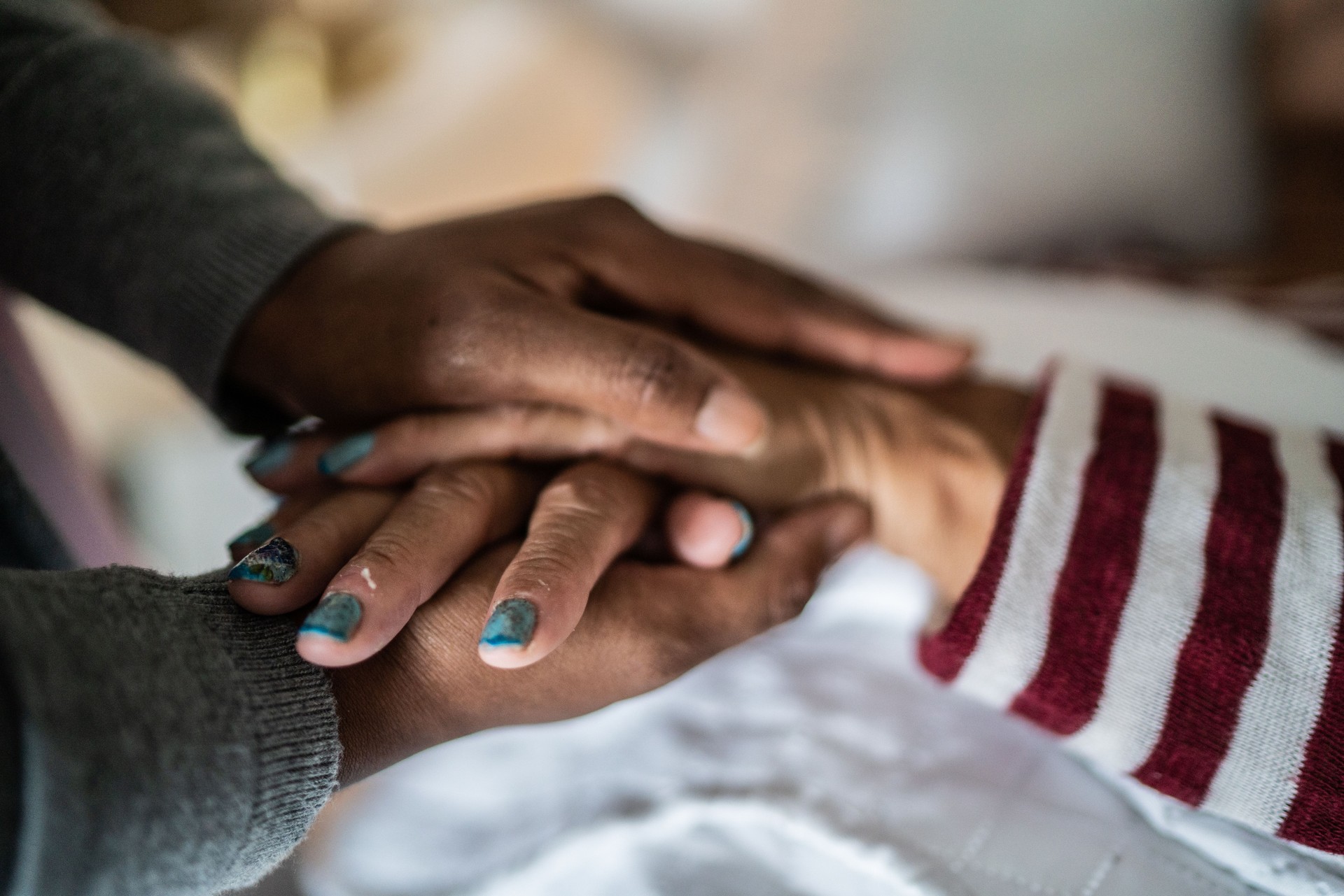 Nurse or home caregiver and senior woman holding hands at home