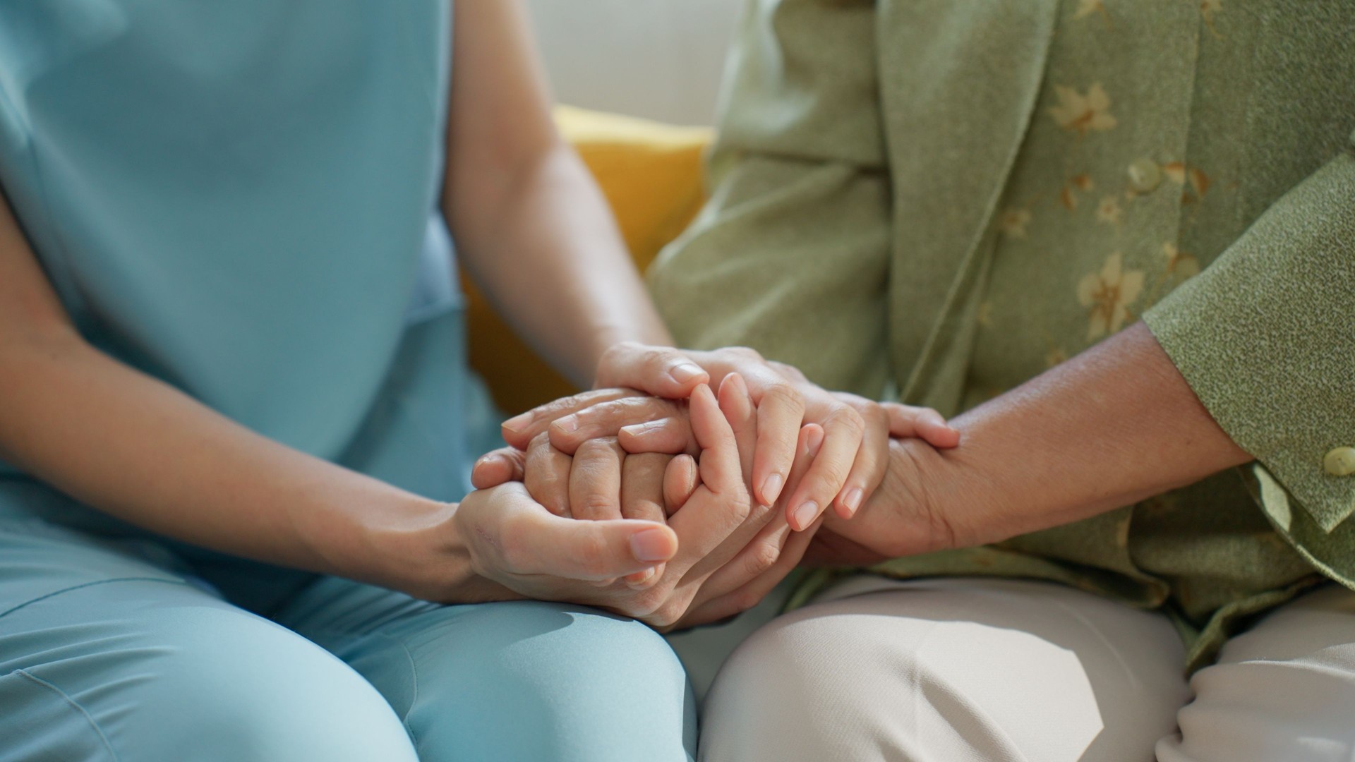 Unrecognized Elderly Woman in Her 70s Sharing a Joyful Moment with Her Mid-adult Caregiver in a Cozy Living Room at Home